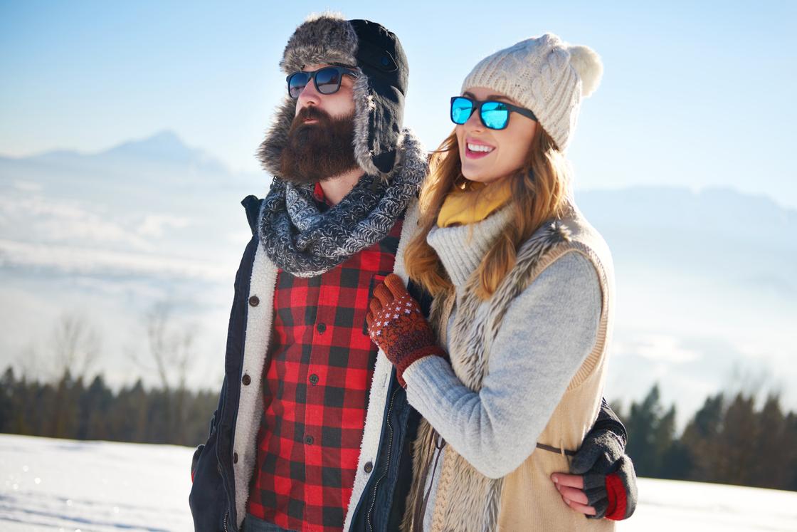 Мужчина и женщина обнимают друг друга на фоне зимнего пейзажа