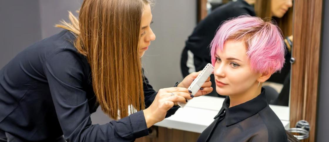 Парикмахер делает укладку девушке с розовыми волосами