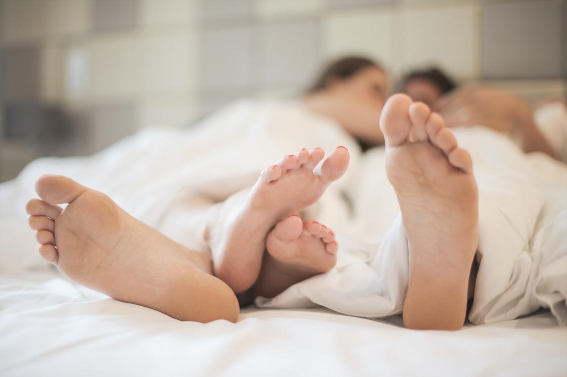 Ноги, лежащих под одеялом мужчины и женщины