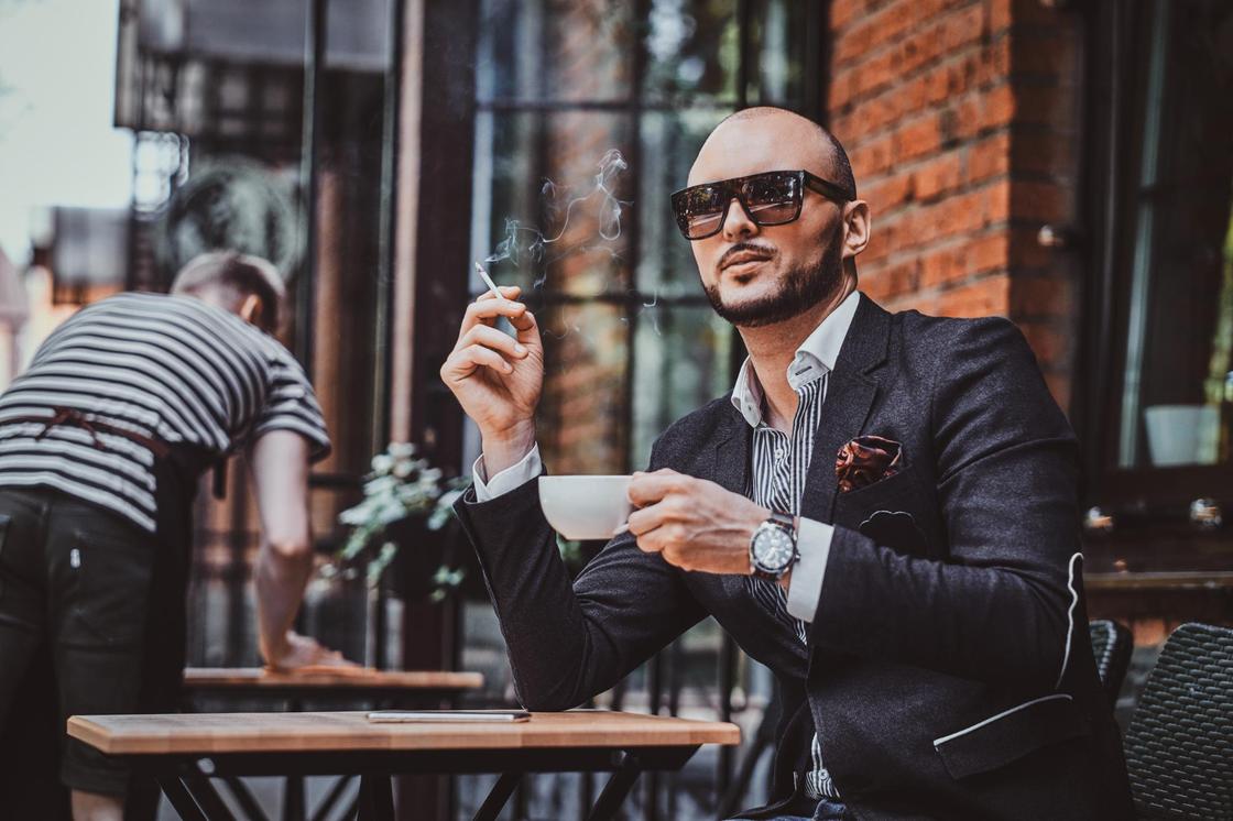 Мужчина пьет кофе и курит сигарету