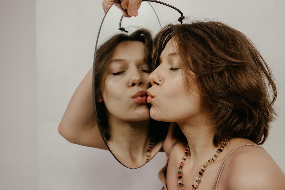 девушка целует свое отражение в зеркале