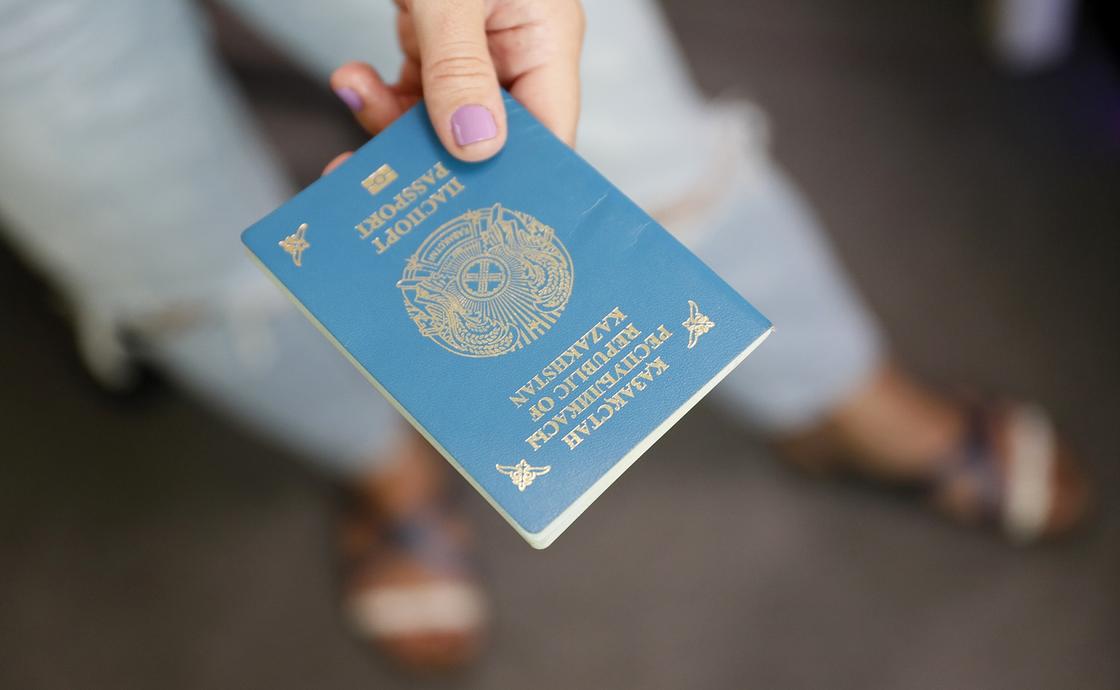 Девушка держит в руке казахстанский паспорт