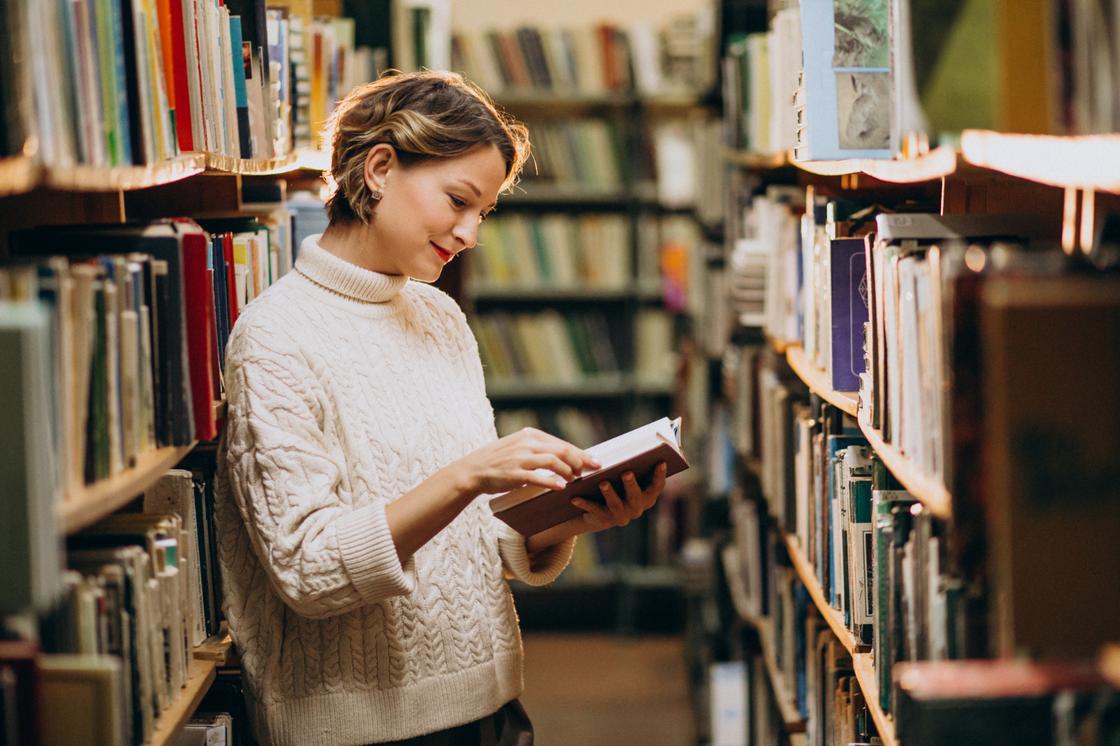 Женщина читает книгу в библиотеке