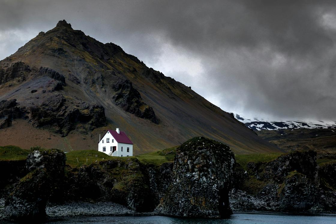 Одинокий домик стоит на фоне горы