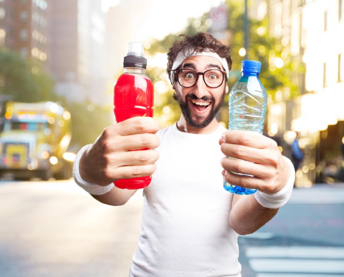 Спортсмен держит в руках бутылку воды и сока
