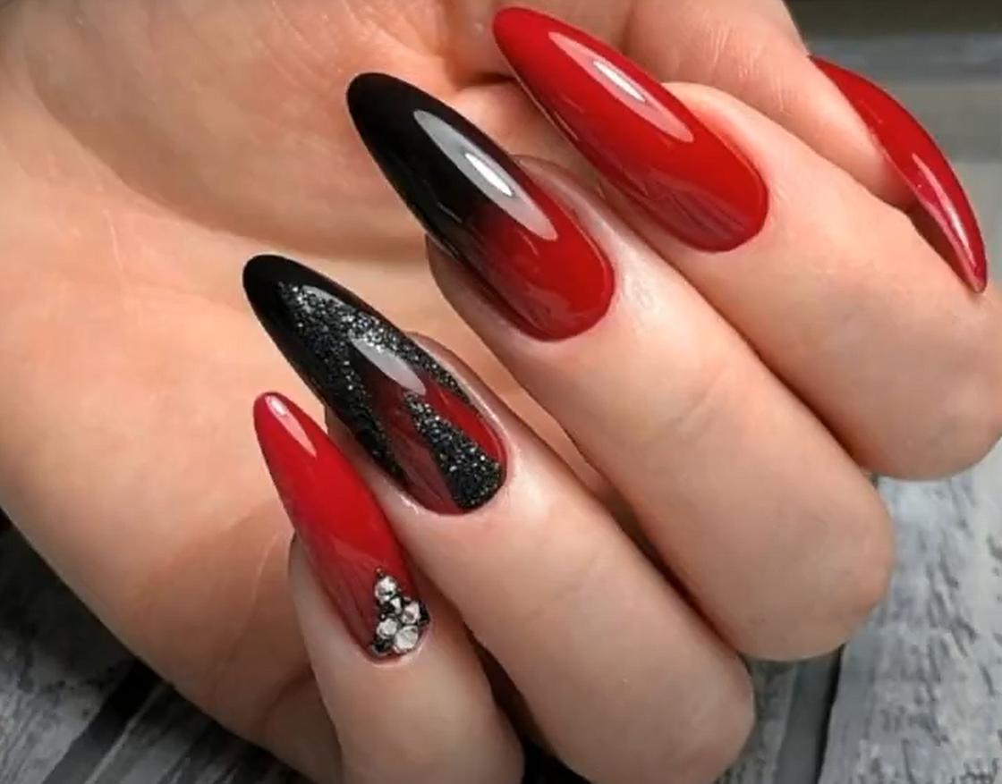 Длинные миндалевидные ногти с красно-черным омбре-маникюром, украшенным стразами
