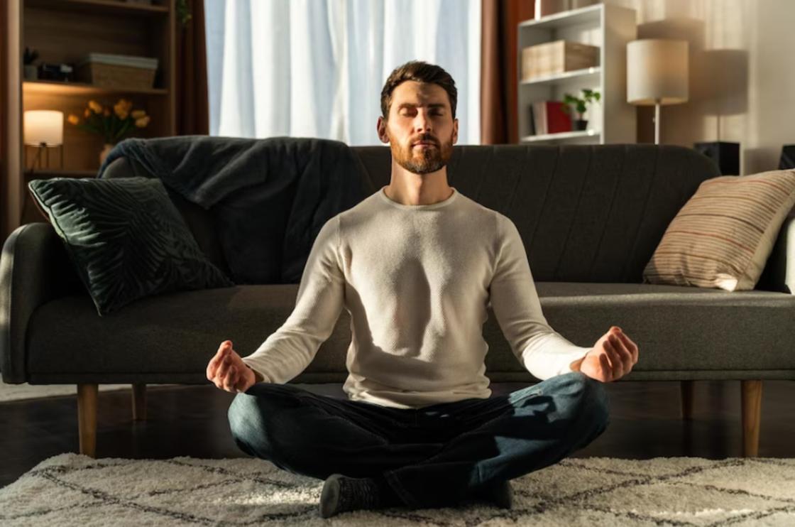Мужчина медитирует на полу квартиры