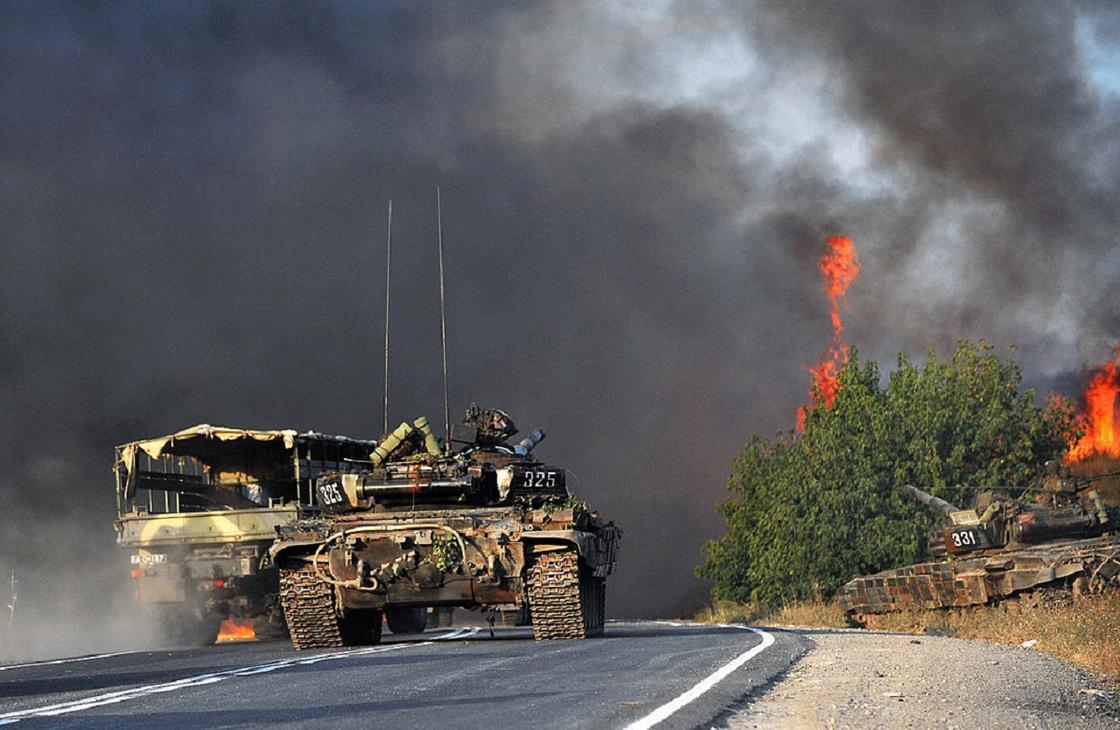 Танк и военная машина на дороге на фоне огня