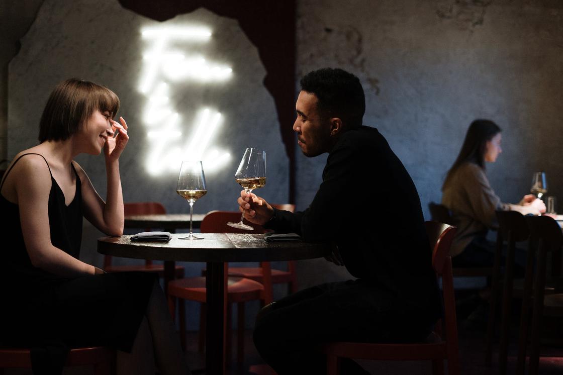 Парень и девушка сидят за столиком в ресторане с бокалами вина