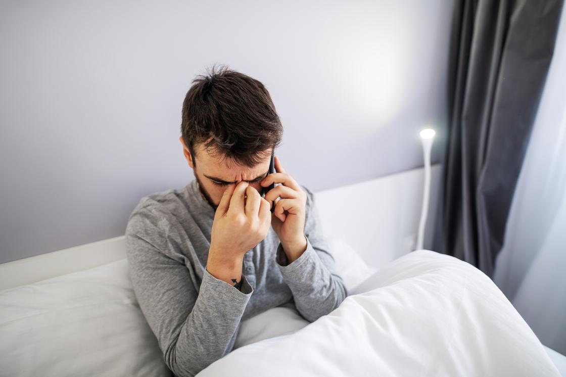 Мужчина отвечает на звонок в постели