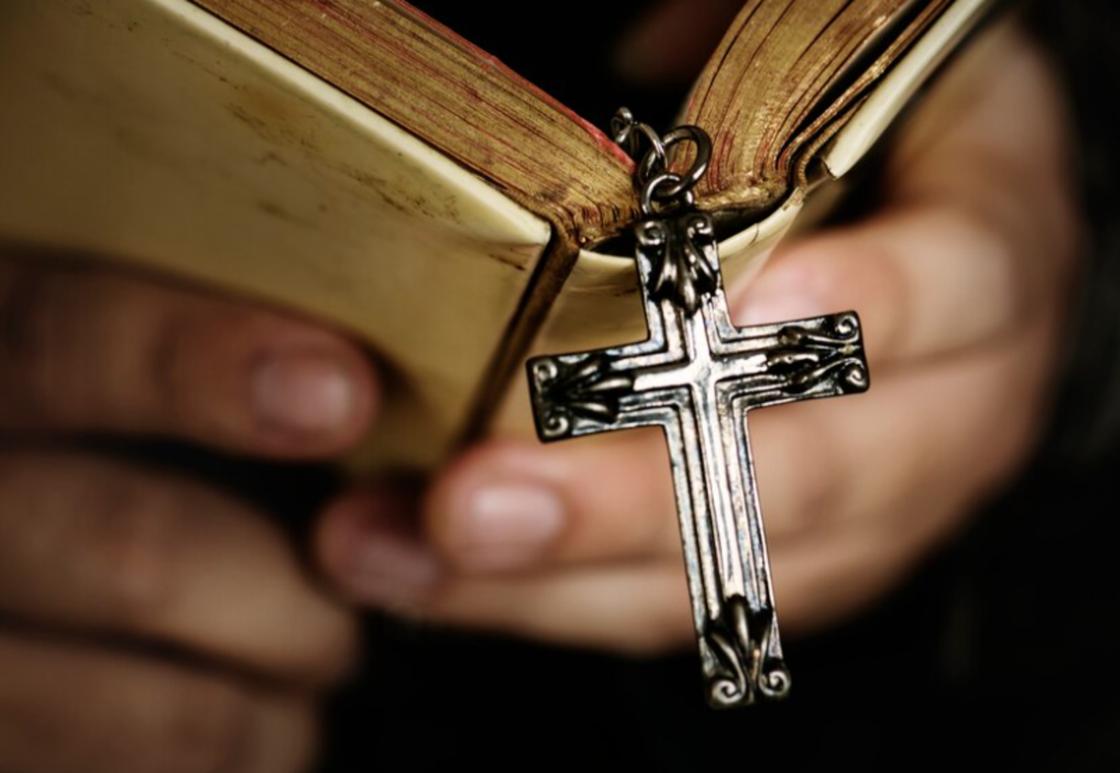 Молитвенник и серебряный крест в руках