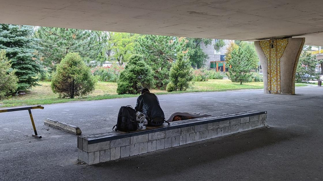 Мужчина сидит под мостом в Алматы