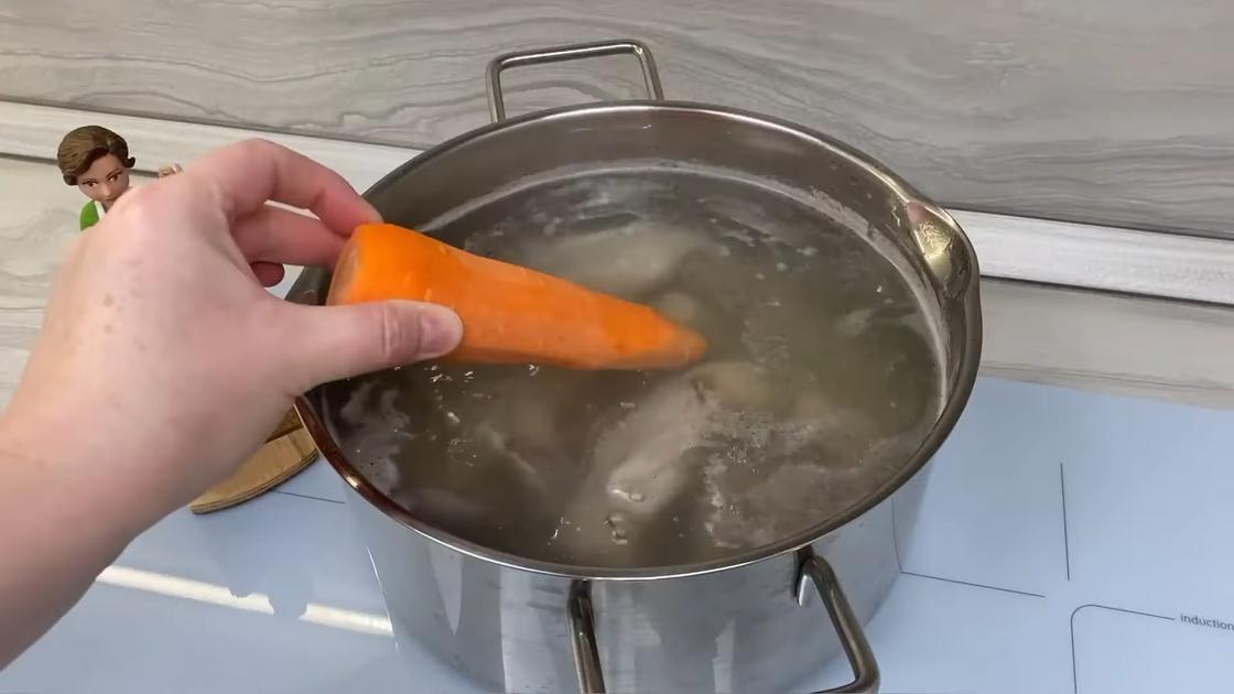 Морковь добавляют в кастрюлю с бульоном и свиным языком