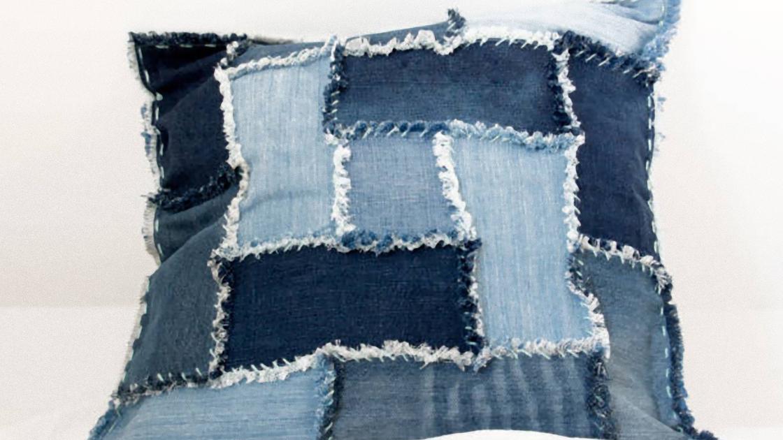 Подушка сшита из лоскутков джинсовой ткани. Лоскутки прямоугольной формы с бахромой по краям
