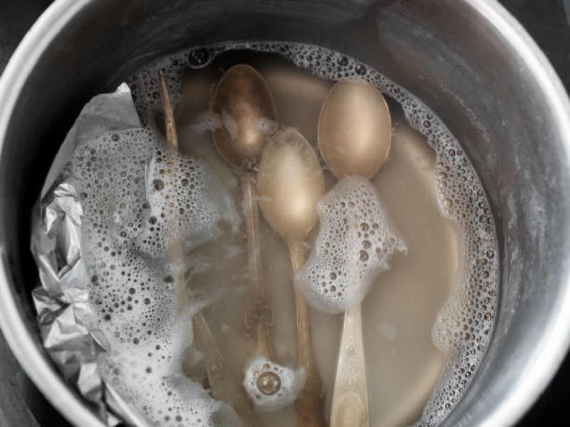 Мельхиоровые ложки сложены в воду в глубокой емкости с фольгой