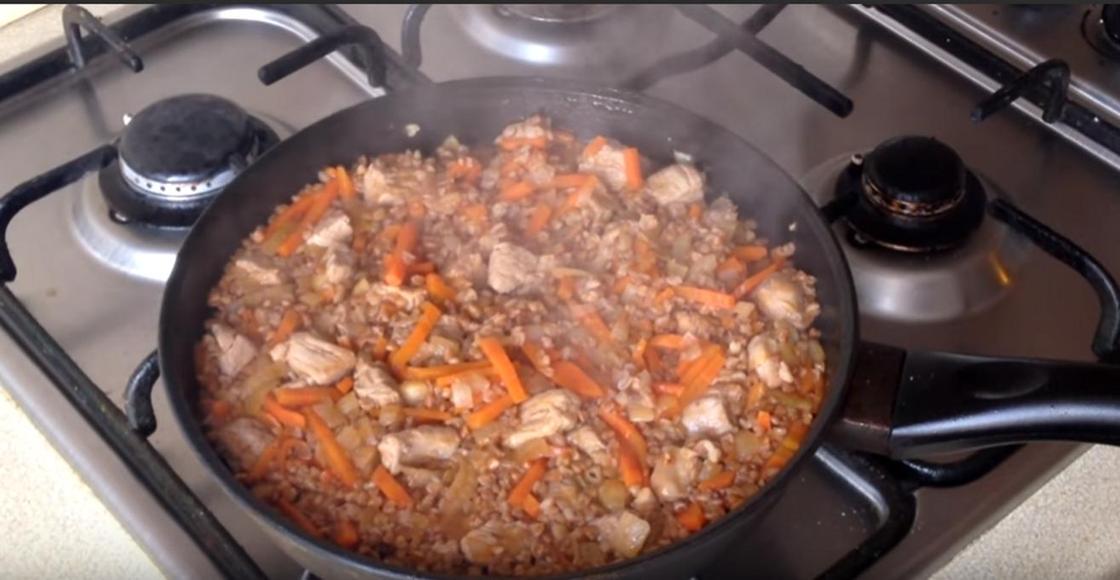 Гречневая каша с мясом и морковью томится на сковороде