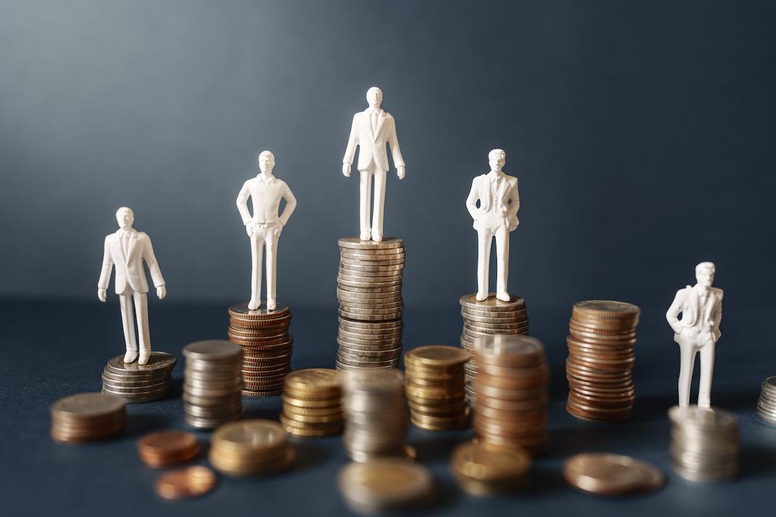 Фигурки людей стоят на столбиках монет