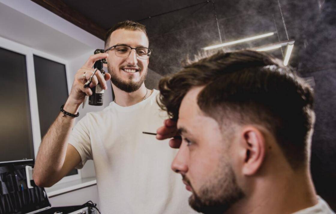 Улыбающийся парикмахер делает укладку клиенту