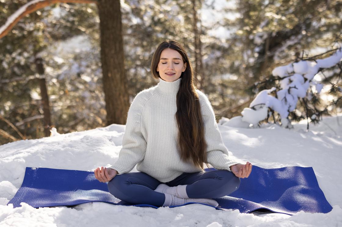 Девушка медитирует на снегу