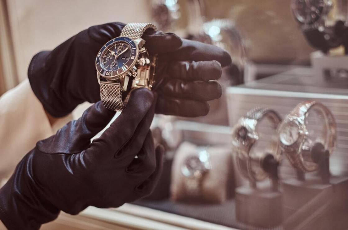 Наручные часы в руках человека в черных перчатках