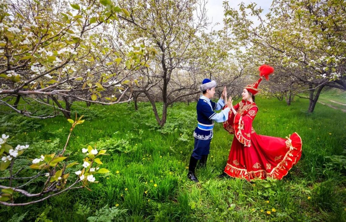 Парень и девушка в казахских национальных костюмах на фоне весенней природы