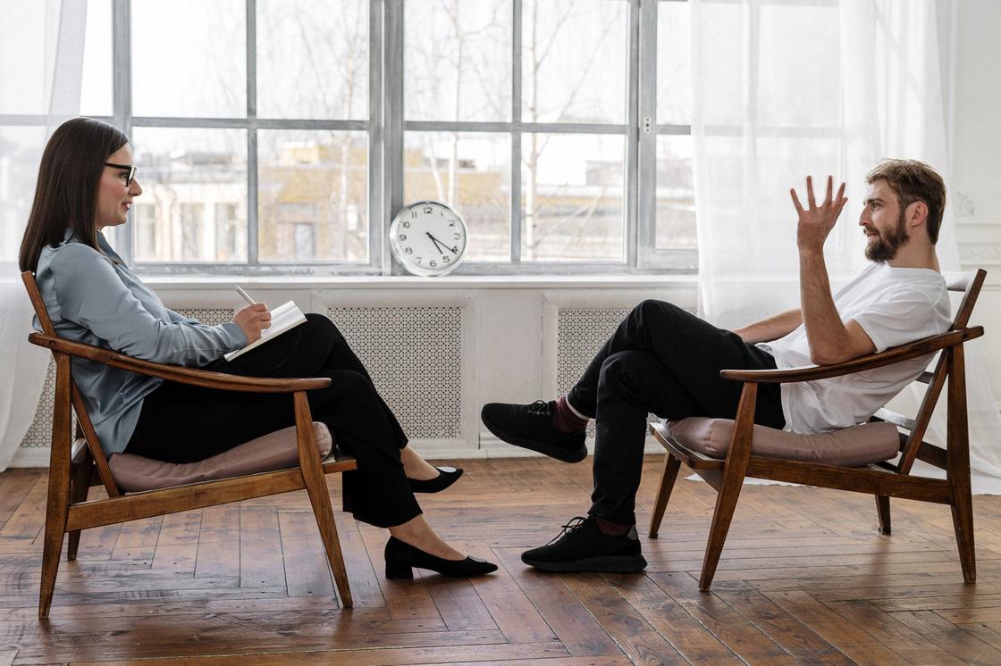 Мужчина и женщина общаются, сидя в креслах друг напротив друга