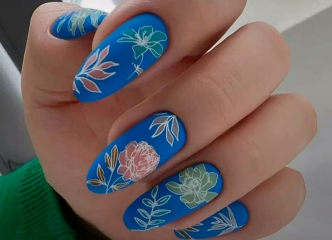 Длинные овальные ногти, покрытые ярким синим лаком и украшенные цветочным узором
