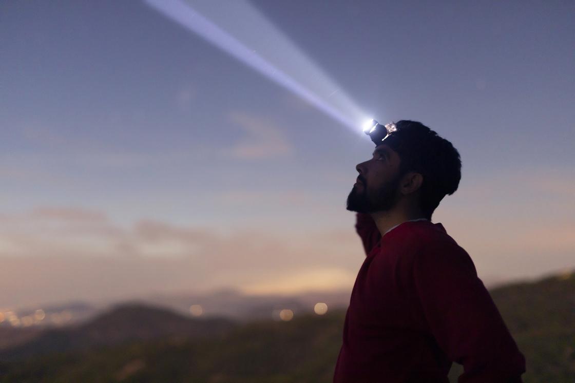 Человек с фонариком на лбу наблюдает за небом