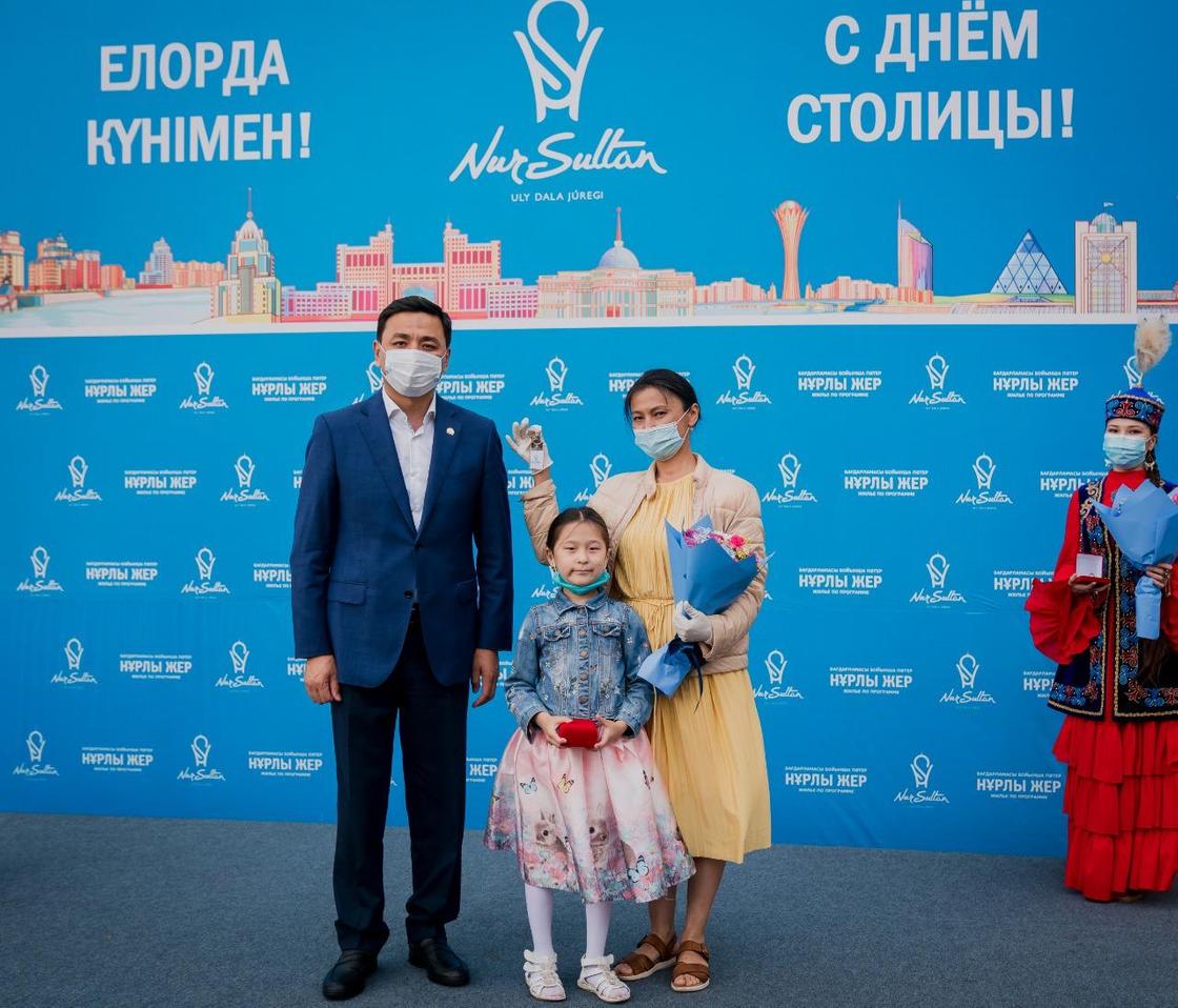 Алтай Кульгинов стоит рядом с женщиной и ребенком