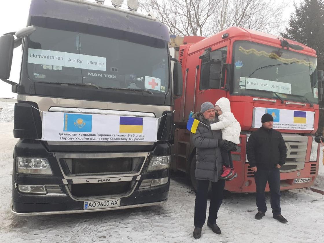 Посол Украины в Казахстане Петр Врублевский с ребенком на руках на фоне грузовиков