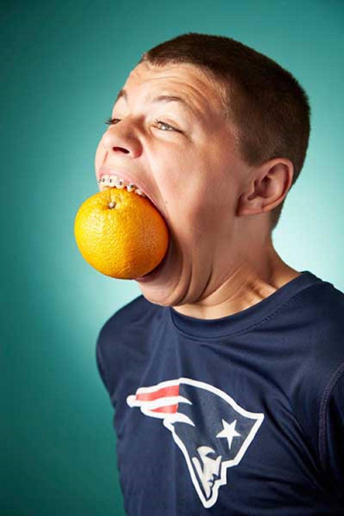 Апельсин во рту мужчины