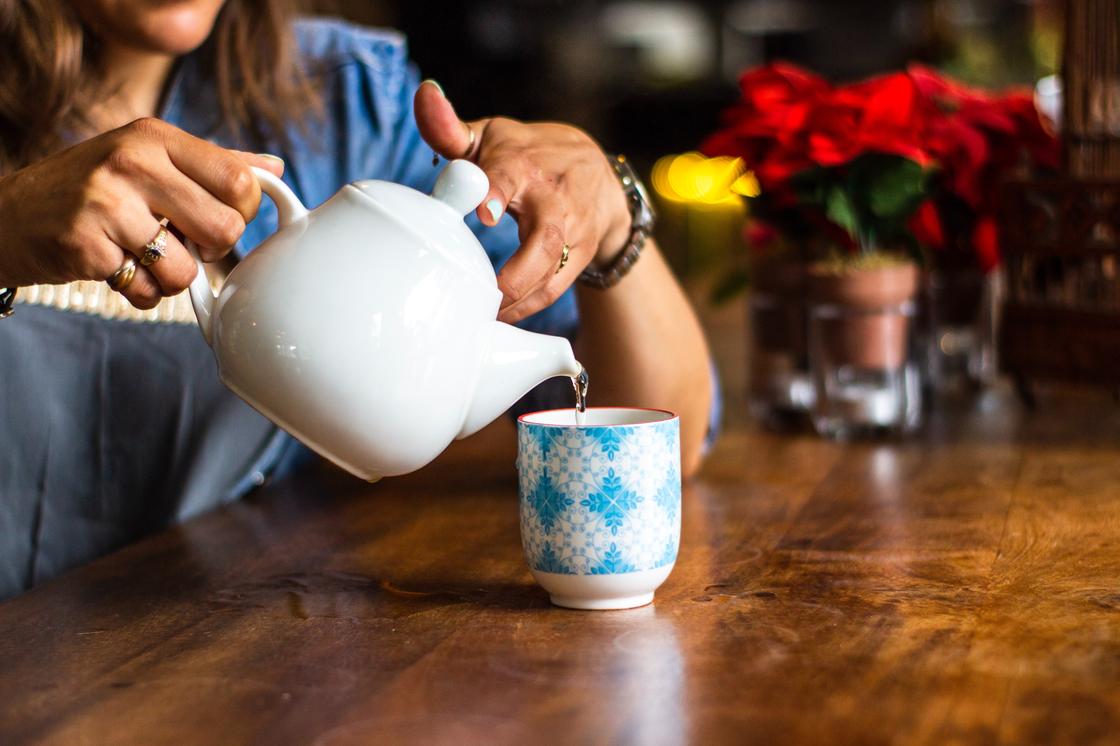 Женщина наливает чай в чашку