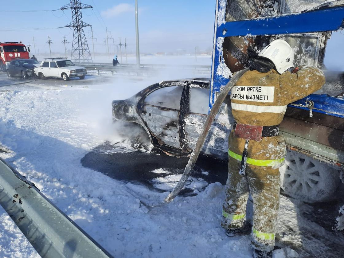 Пожарный тушит сгоревшее авто