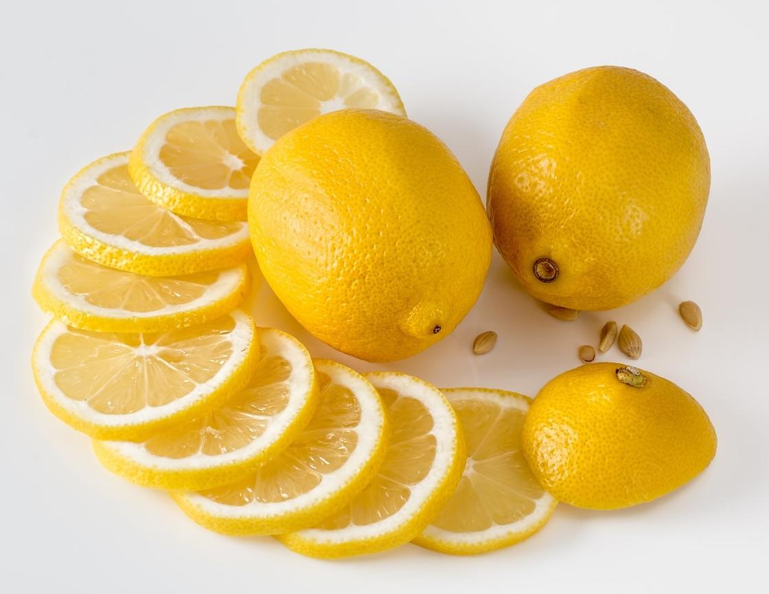 Целые и нарезанные дольками лимоны лежат на столе