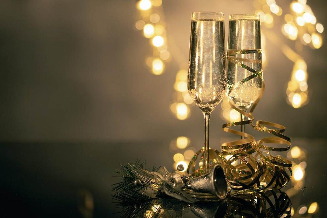 Бокалы с шампанским и новогодняя мишура на фоне огоньков