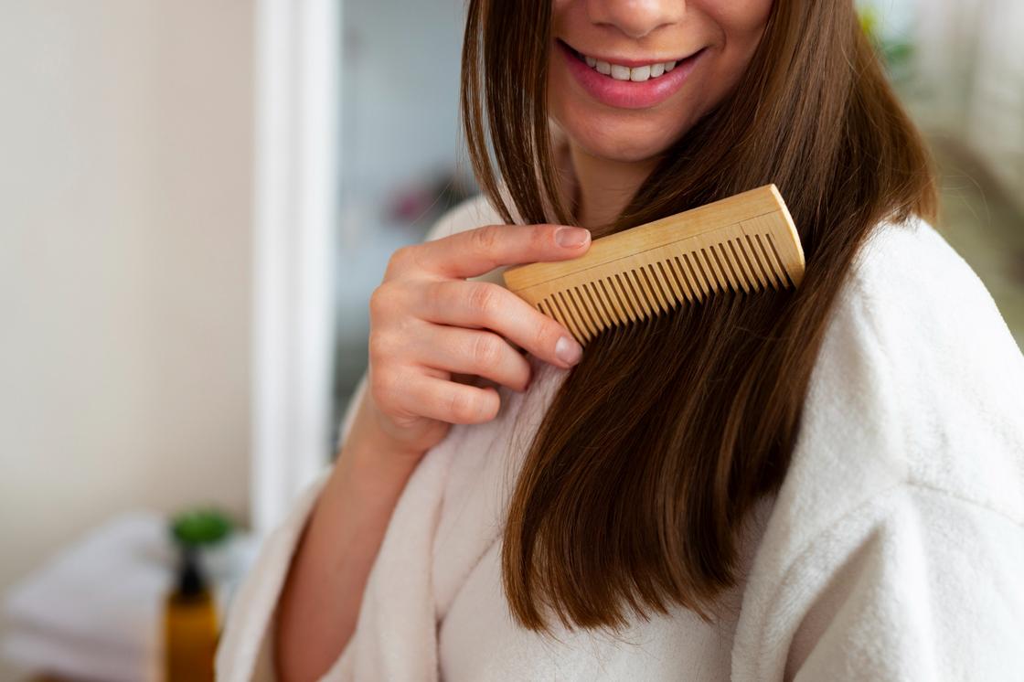 Девушка расчесывает волосы деревянным гребнем