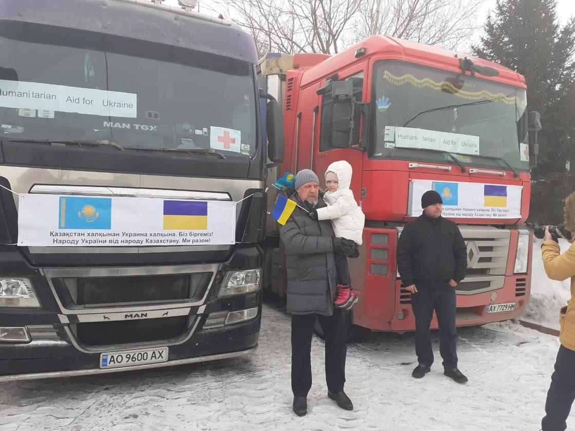 Посол Украины в Казахстане Петр Врублевский с ребенком на руках на фоне грузовиков