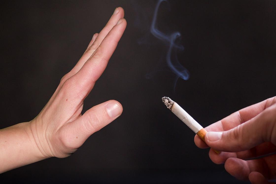 Останавливающий жест руки  на сигарету, которую предлагает другая рука