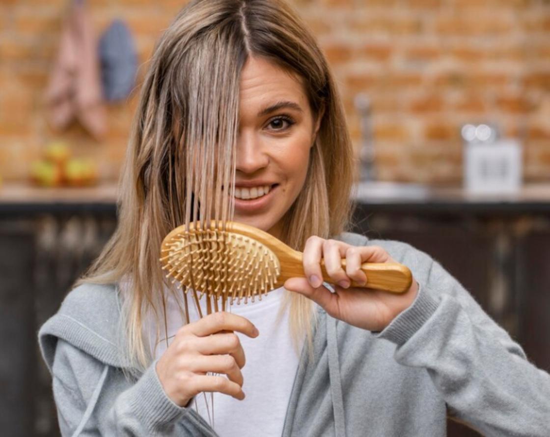 Девушка расчесывает волосы деревянной расческой