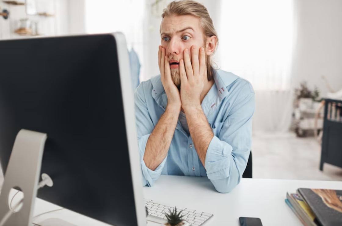 Испуганный мужчина смотрит на монитор компьютера