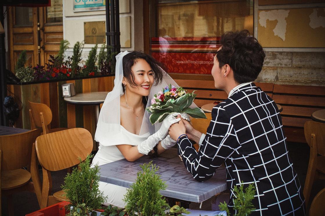 Жених и невеста сидят за столик в кафе, держась за руки