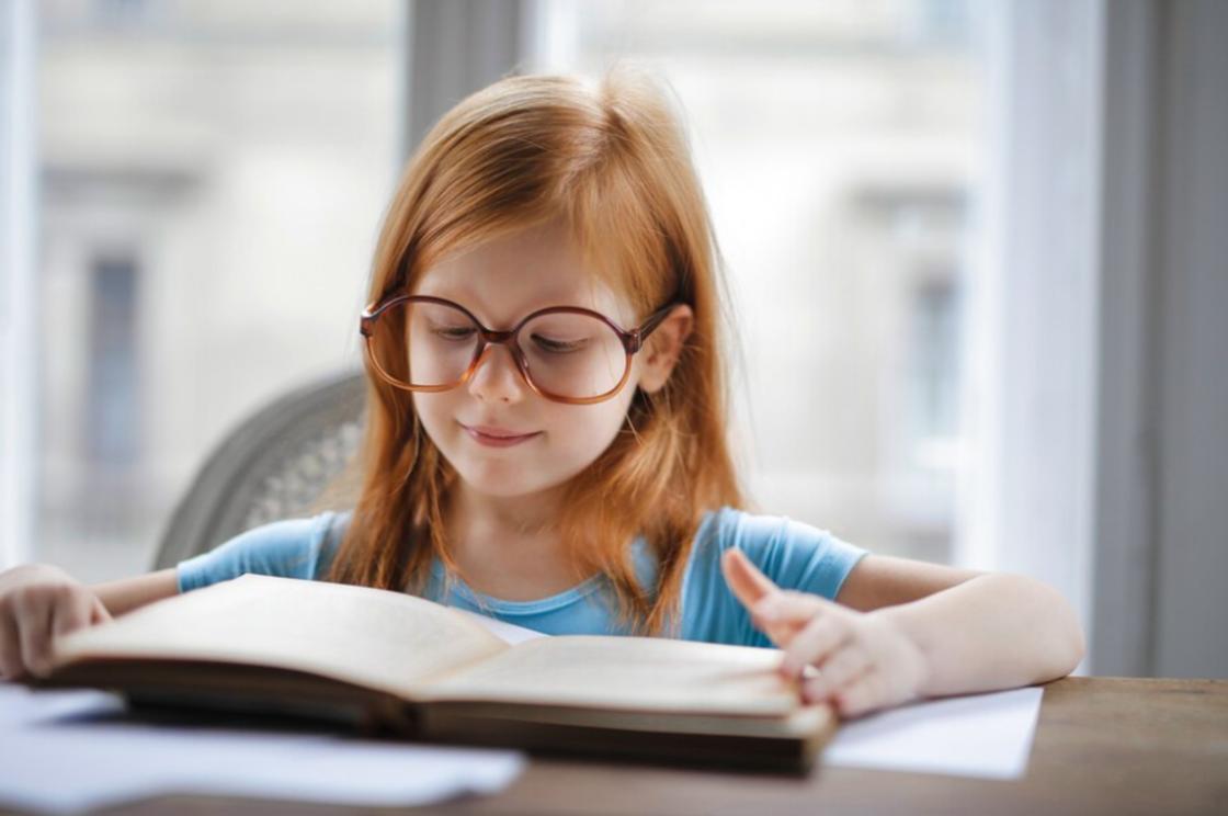 Девочка в очках читает книгу