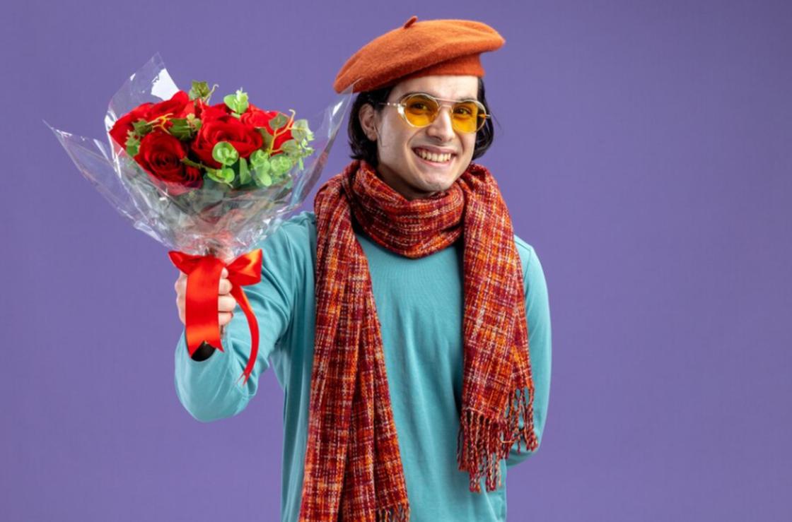Яркий мужчина в очках протягивает букет цветов