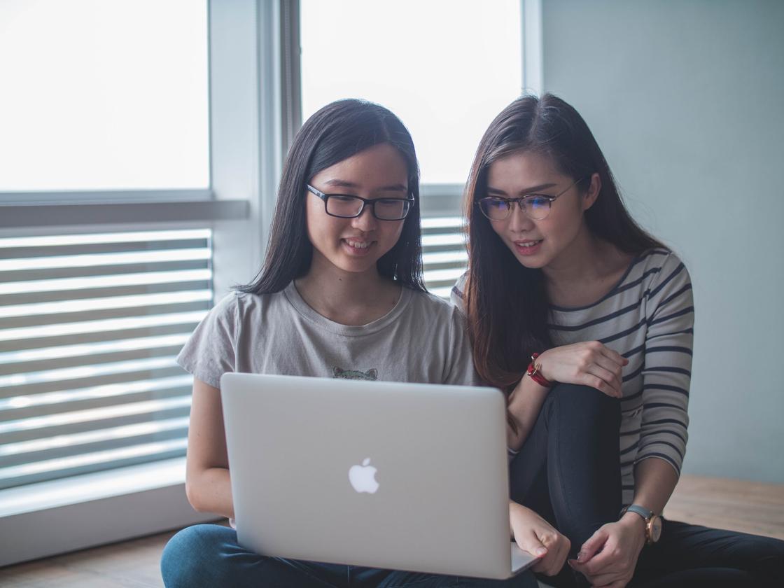 Две девушки смотрят на экран ноутбука