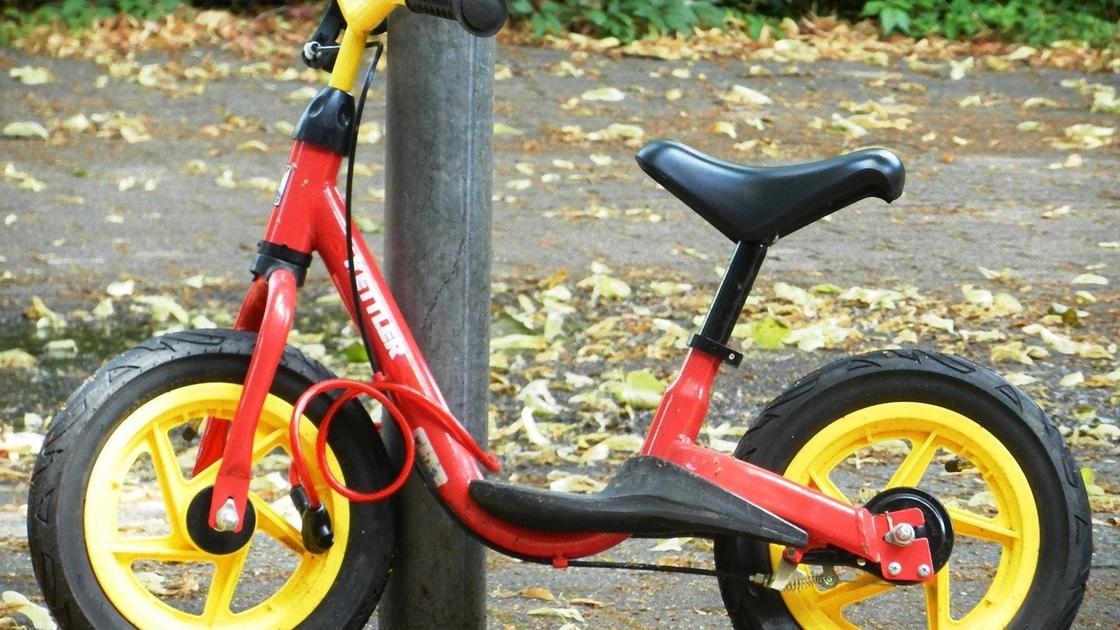 Детский двухколесный велосипед с красной рамой и желтыми ободками на колесах