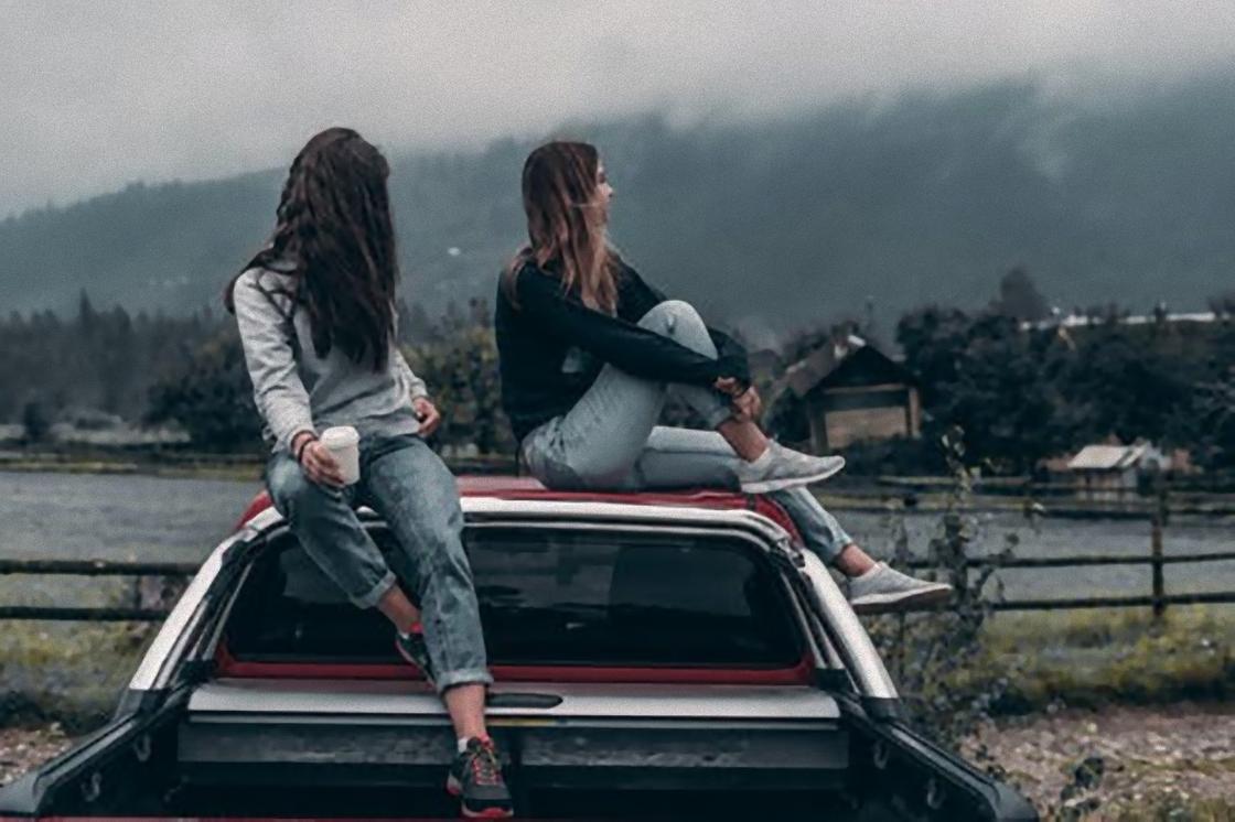 Девушки сидят на крыше автомобиля