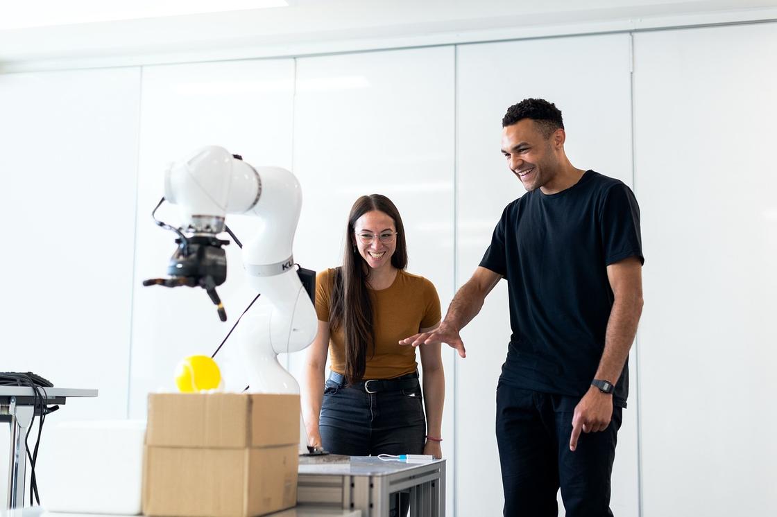 Мужчина и женщина радуются, глядя, как работает робот