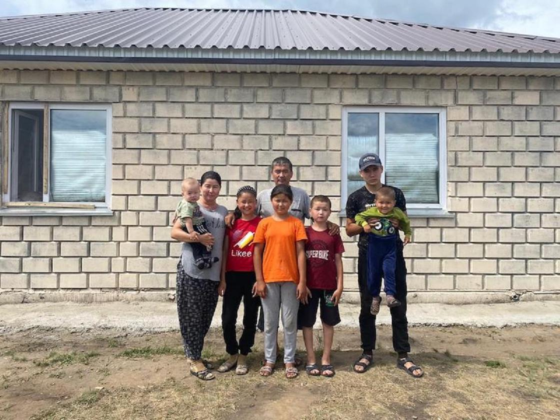 Семья переселенцев стоит возле своего дома
