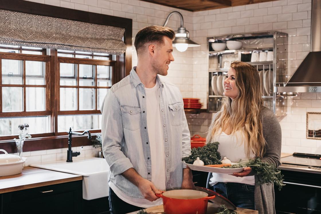 Мужчина и женщина улыбаются, стоя на кухне и глядя друг на друга