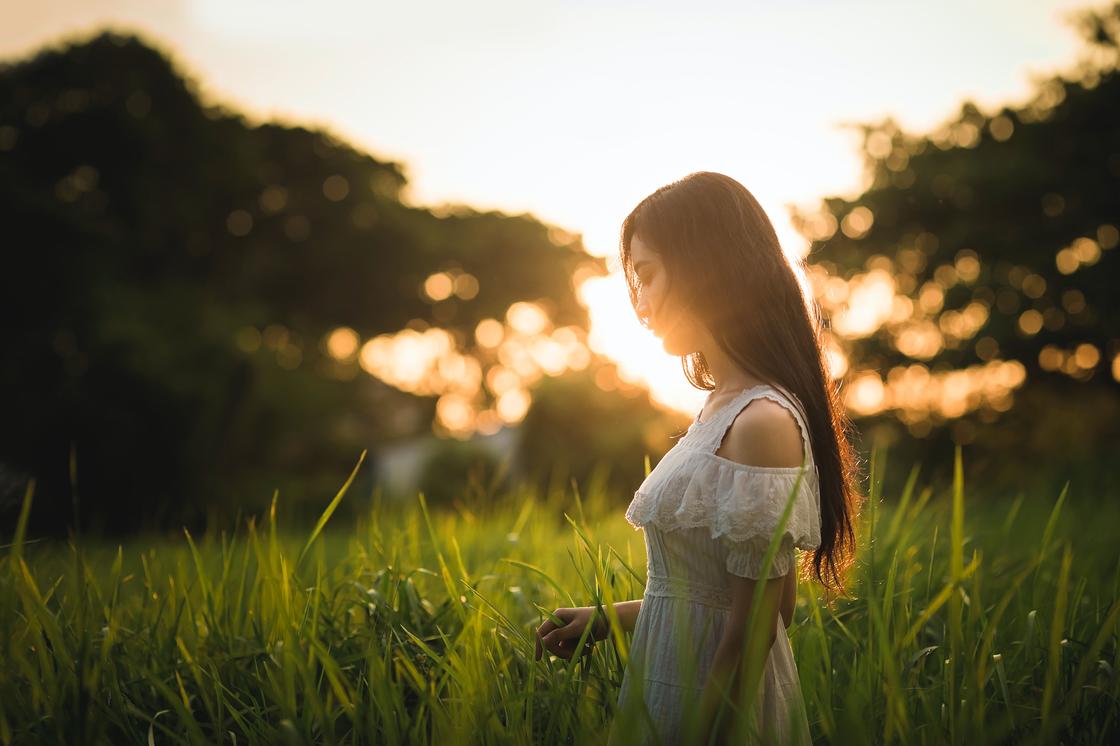 Девушка стоит в траве на фоне солнца